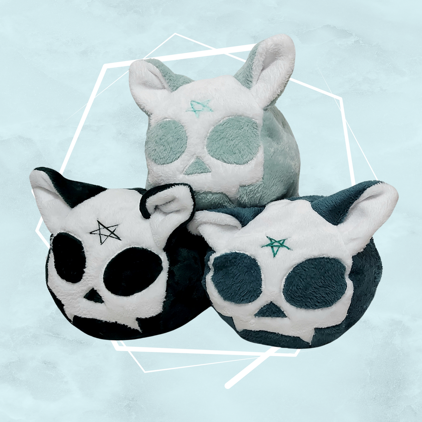 Different colored soft toy plushies with a cat skull design with a pentagram on their forehead and cat ears on top, handmade by UK artist Freya's Madpeak