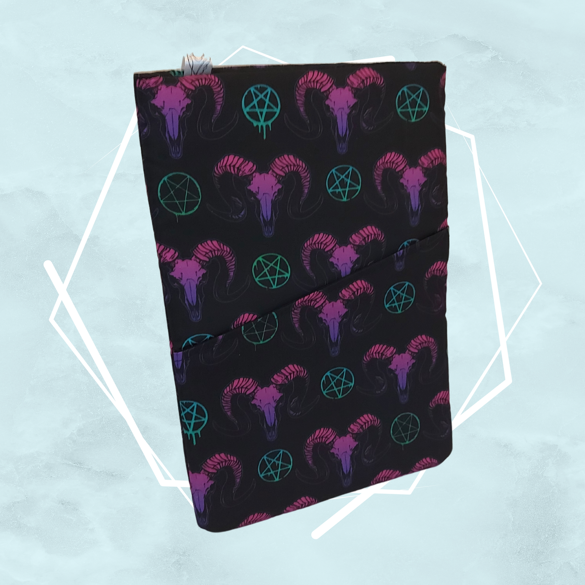 A gothic black booksleeve with a pattern of goat heads and occult symbols in purple, green and pink colors, made for readers to keep books safe