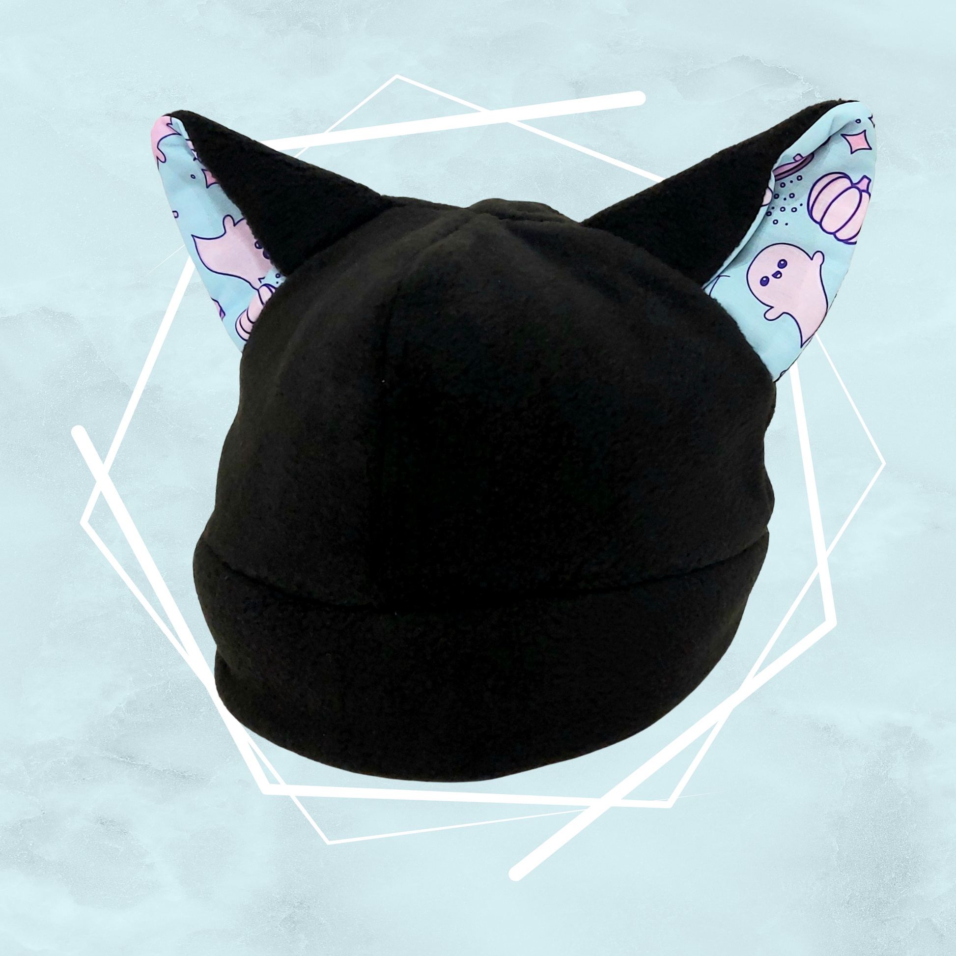 A handcrafted black nekomimi beanie with cat ears featuring a quirky pattern with cute ghost-like figures on a blue background.