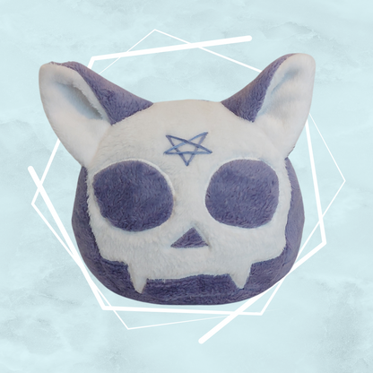 A plushie of a purple cat skull with a pentagram design, made of soft fabric, intended for Halloween season.
