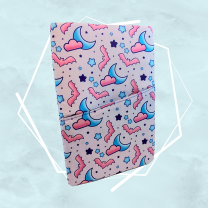 A booksleeve with a pattern of moons and bats, predominantly in pink and blue colors, made by Freya's Madpeak in the UK