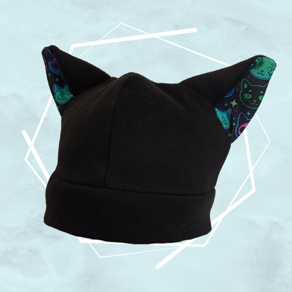 Black handmade fleece beanie hat with cat ears and whimsical pattern, made by UK-based artist